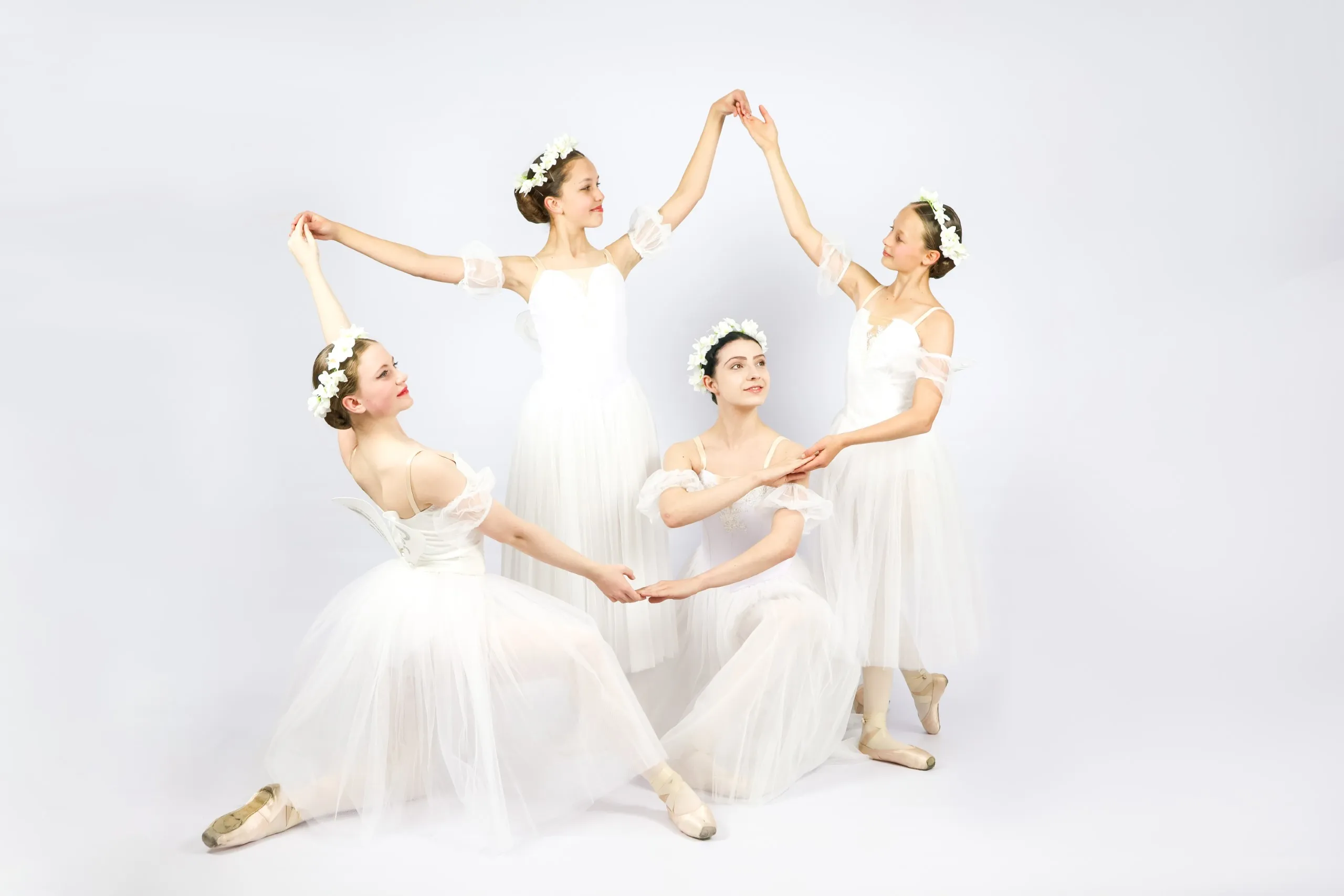 A photo from a photoshoot for YRBC's production of Les Sylphides. 4 dancers stand in a circle, interlocking hands.
