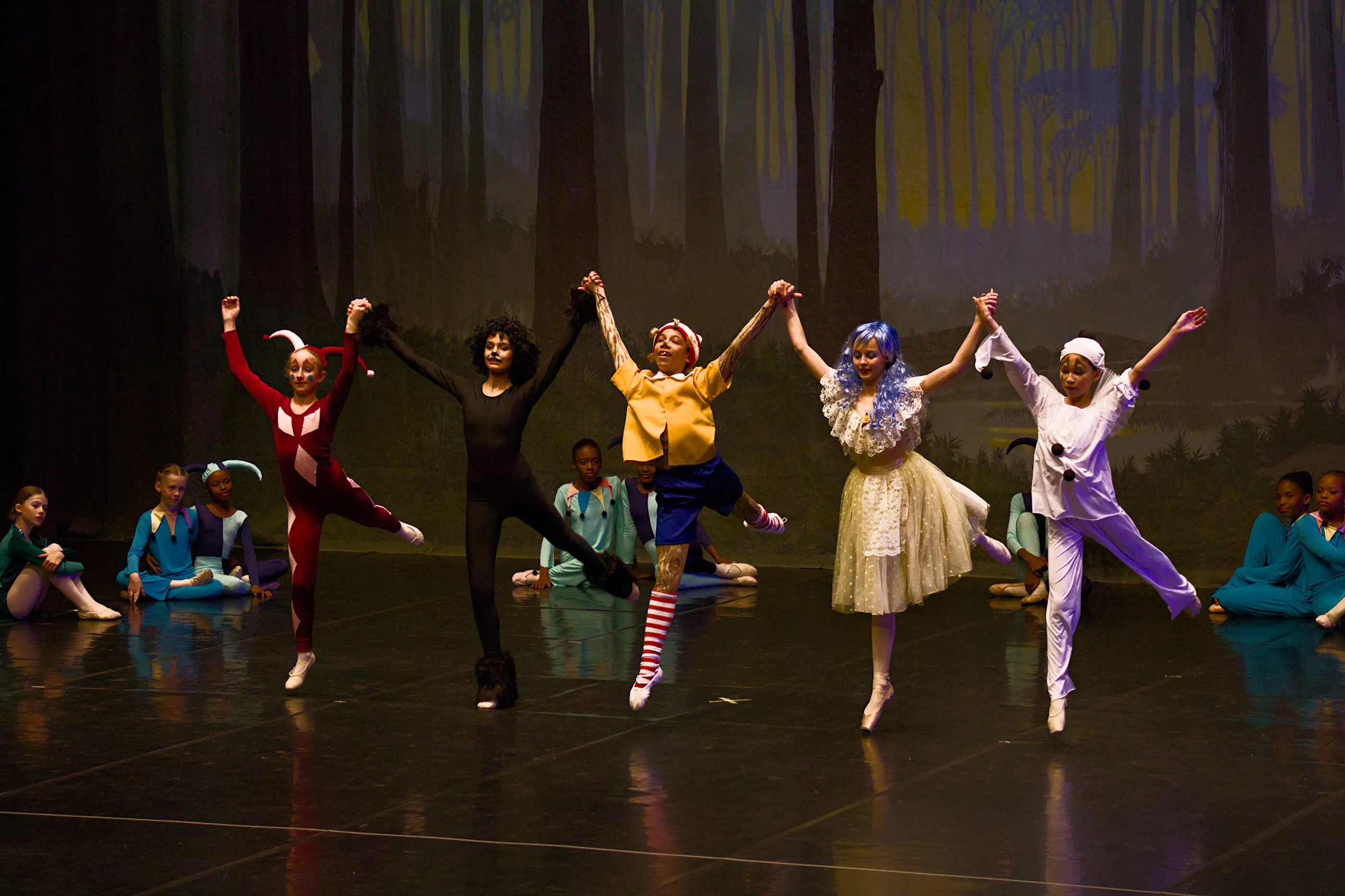 A group of 5 ballet dancers jump together while holding hands as part of YRBC's 2023 performance of Pinocchio and the Golden Key.